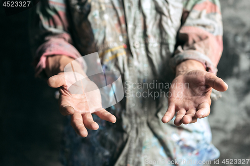 Image of Male beggar hands seeking money on the wooden floor at public path way