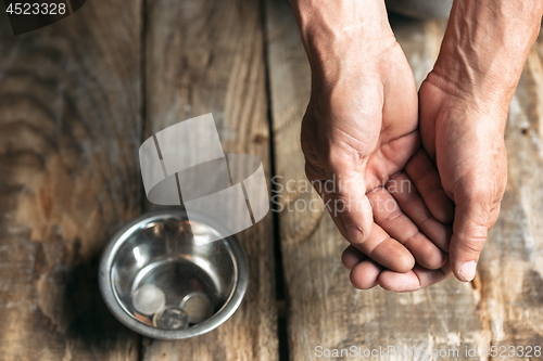 Image of Male beggar hands seeking money on the wooden floor at public path way