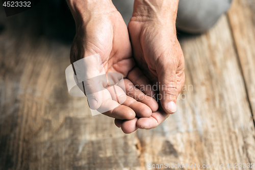 Image of Male beggar hands seeking money on the wooden floor at public path way