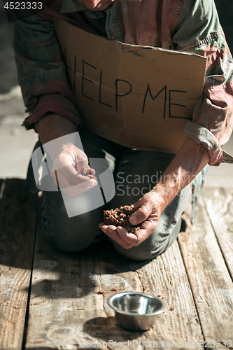 Image of Male beggar hands seeking money on the wooden floor at public path way