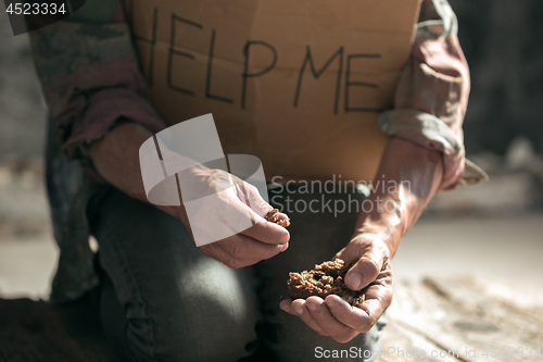 Image of Male beggar hands seeking money on the wooden floor at public path way