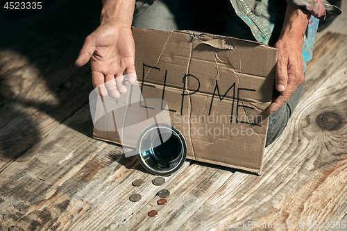 Image of Male beggar hands seeking money on the wooden floor at public path way