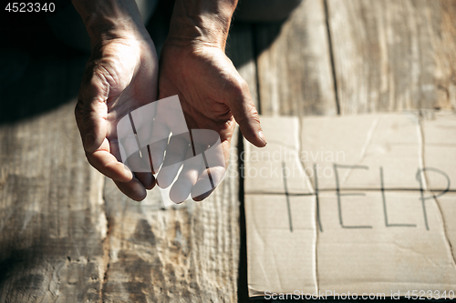 Image of Male beggar hands seeking money on the wooden floor at public path way