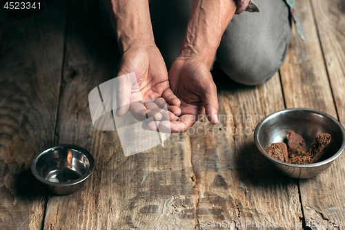 Image of Male beggar hands seeking money on the wooden floor at public path way