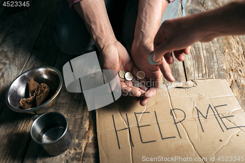 Image of Male beggar hands seeking money on the wooden floor at public path way