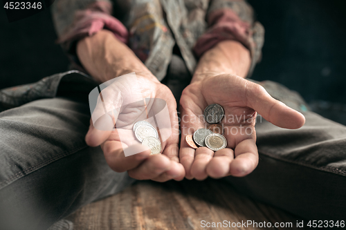 Image of Male beggar hands seeking money on the wooden floor at public path way