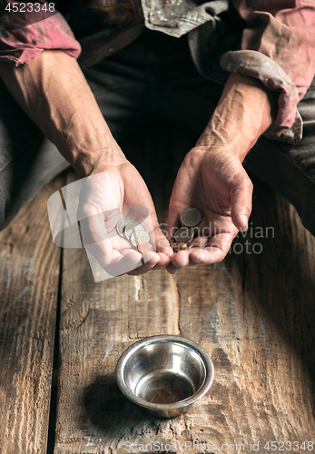 Image of Male beggar hands seeking money on the wooden floor at public path way