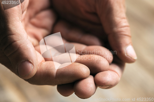 Image of Male beggar hands seeking money on the wooden floor at public path way