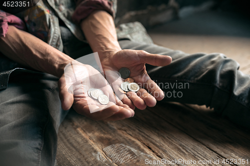 Image of Male beggar hands seeking money on the wooden floor at public path way