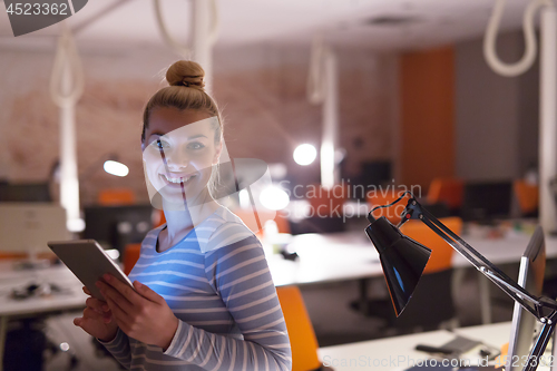 Image of woman working on digital tablet in night office