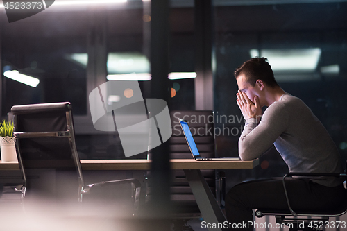 Image of man working on laptop in dark office