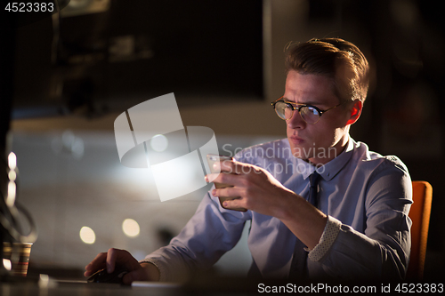 Image of man using mobile phone in dark office
