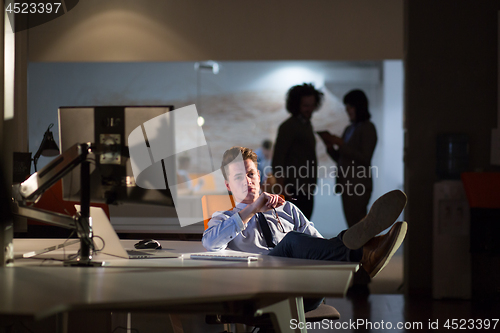 Image of businessman sitting with legs on desk at office