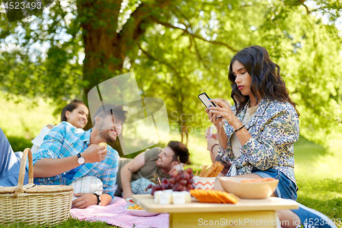 Image of woman using smartphone at picnic with friends