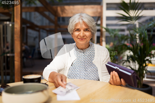 Image of senior woman with money paying bill at cafe