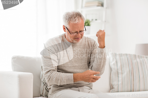 Image of unhappy senior man suffering elbow pain at home