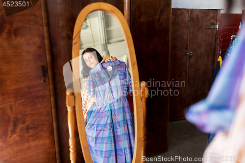 Image of woman with dress at vintage clothing store mirror