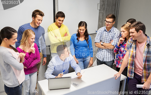 Image of students and teacher with papers and laptop