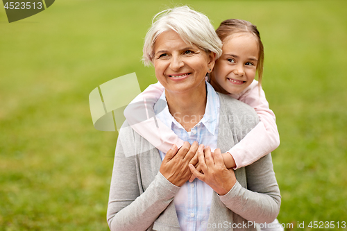 Image of granddaughter hugging grandmother at summer park