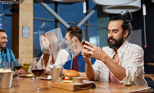 Image of man messaging on smartphone at restaurant