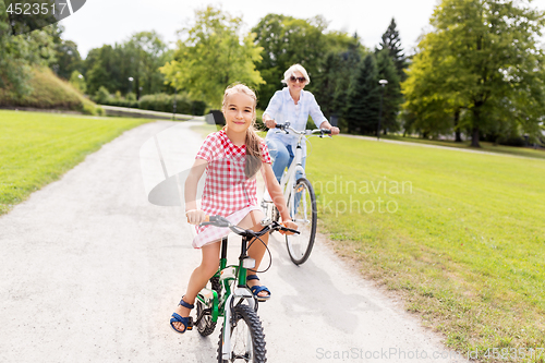 Image of grandmother and granddaughter cycling at park