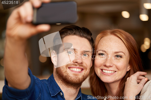 Image of couple taking selfie by smartphone at restaurant