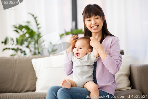 Image of happy young asian mother with little baby at home