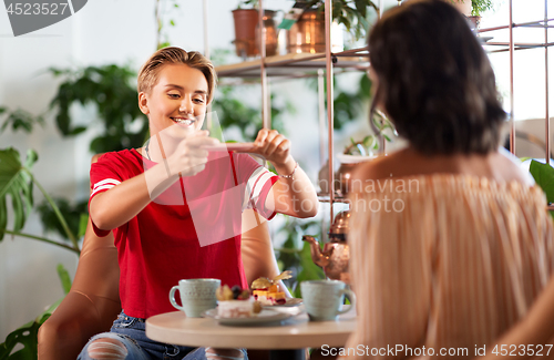 Image of female friends drinking tea with cake at cafe