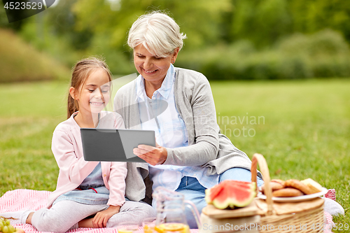 Image of grandmother and granddaughter with tablet at park