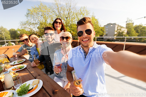 Image of happy friends taking selfie at rooftop party