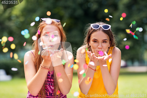 Image of teenage girls blowing confetti off hands in park