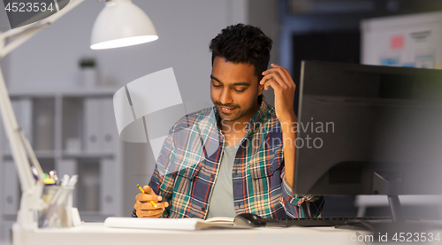 Image of creative man with notebook working at night office