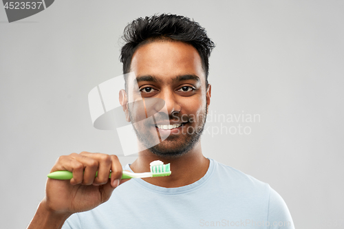 Image of indian man with toothbrush over grey background