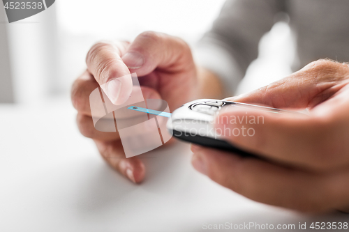 Image of senior man with glucometer checking blood sugar