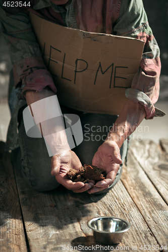 Image of Male beggar hands seeking money on the wooden floor at public path way