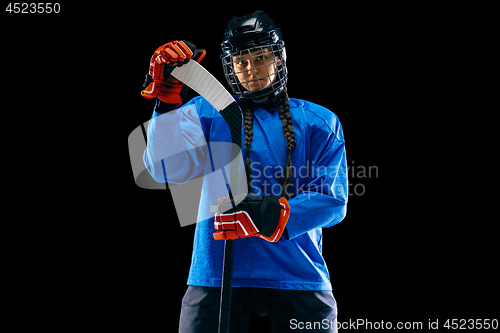 Image of Young female hockey player with the stick isolated on black background