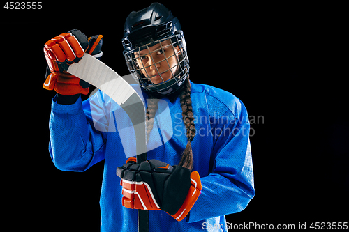 Image of Young female hockey player with the stick isolated on black background