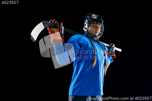 Image of Young female hockey player with the stick isolated on black background