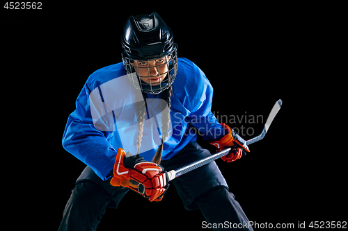 Image of Young female hockey player with the stick isolated on black background