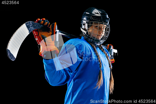 Image of Young female hockey player with the stick isolated on black background