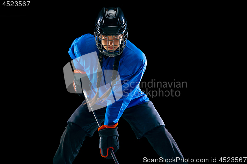 Image of Young female hockey player with the stick isolated on black background