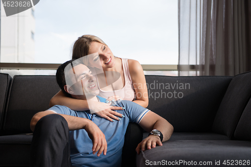 Image of young handsome couple hugging on the sofa