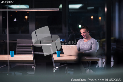 Image of man working on laptop in dark office