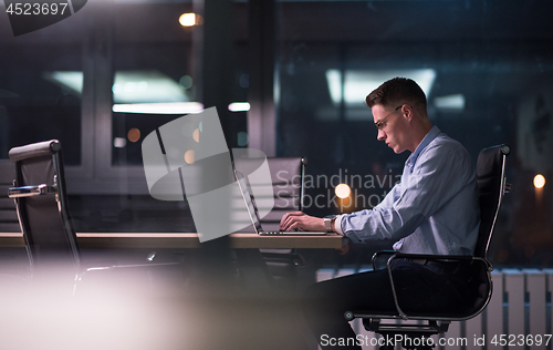 Image of man working on laptop in dark office