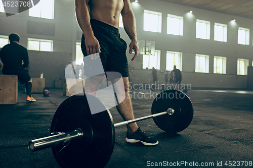 Image of Fit young man lifting barbells working out in a gym