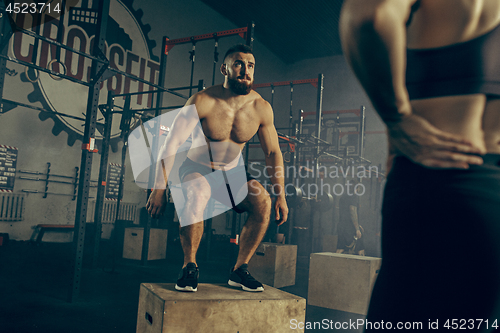 Image of Man jumping during exercises in the fitness gym. CrossFit.