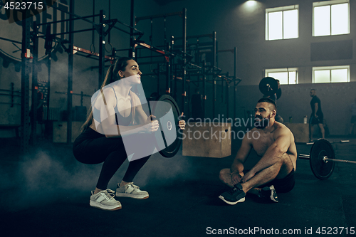 Image of Fit young woman lifting barbells working out in a gym