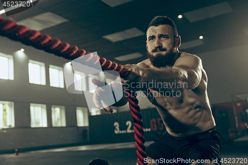 Image of Men with battle rope battle ropes exercise in the fitness gym.