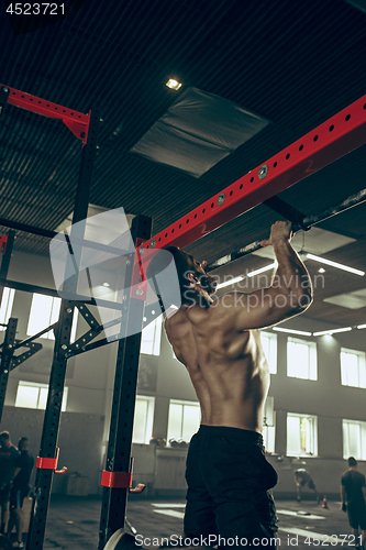 Image of Concept: power, strength, healthy lifestyle, sport. Powerful attractive muscular man at CrossFit gym