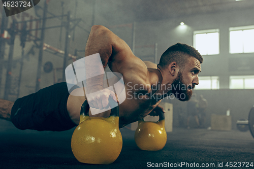 Image of Fit young man lifting barbells working out in a gym